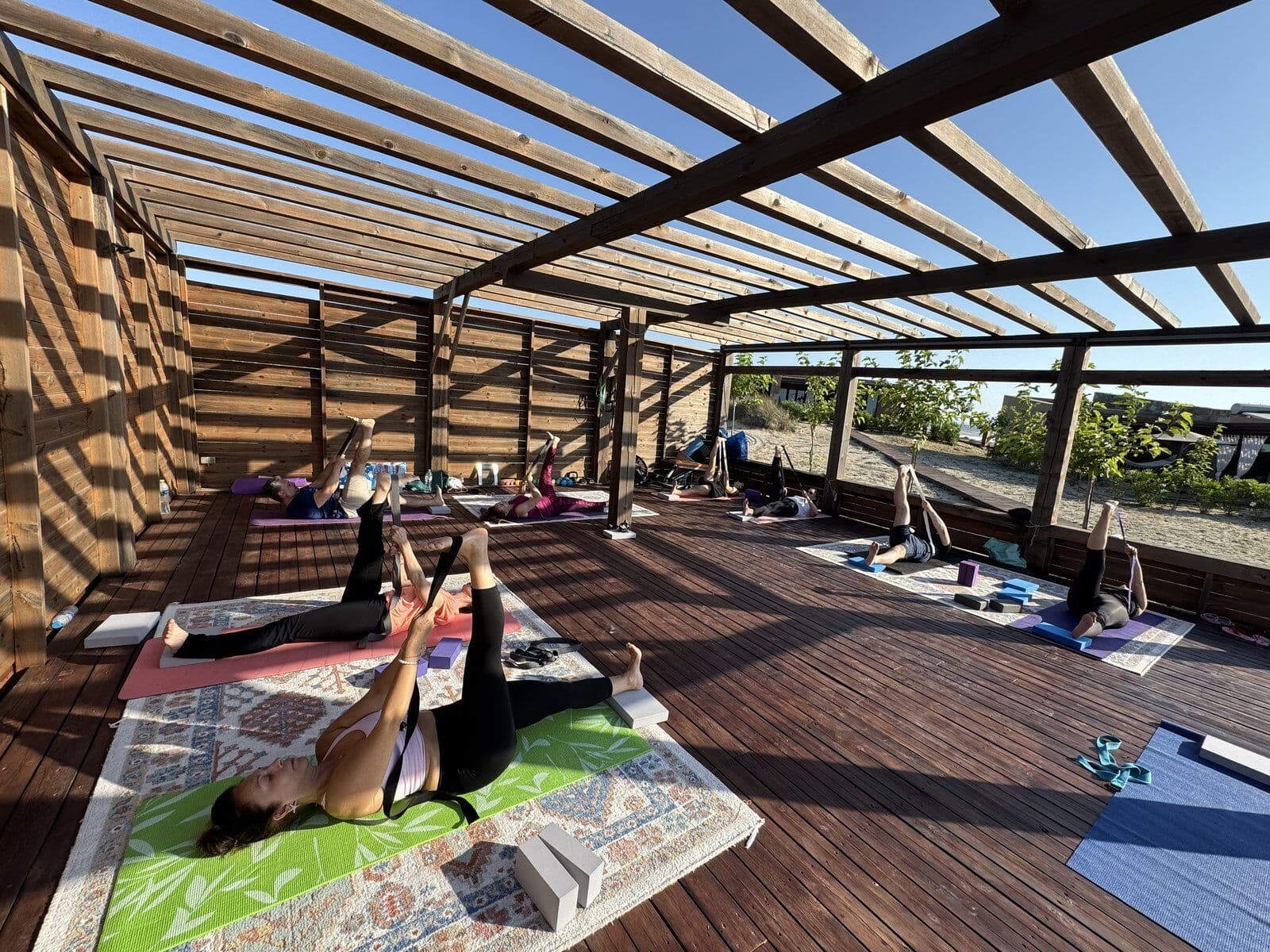 Group yoga practice on a wooden deck by the Aegean sea