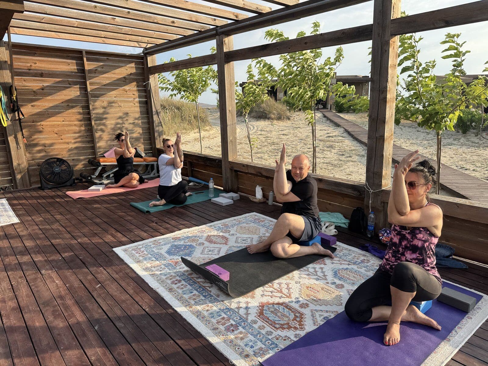 Seated yoga practice on deck with traditional rugs