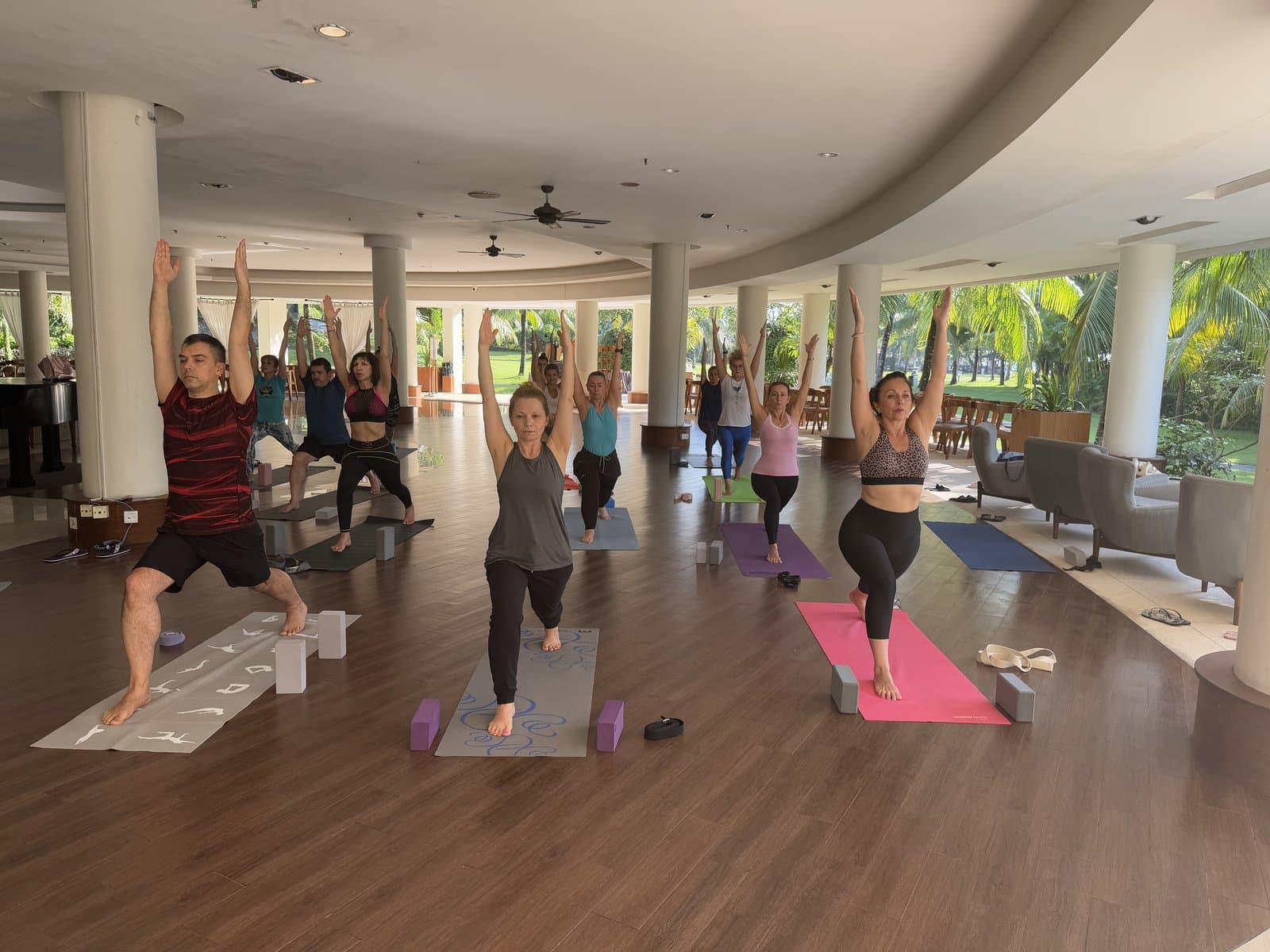 Indoor warrior pose class with tropical garden views