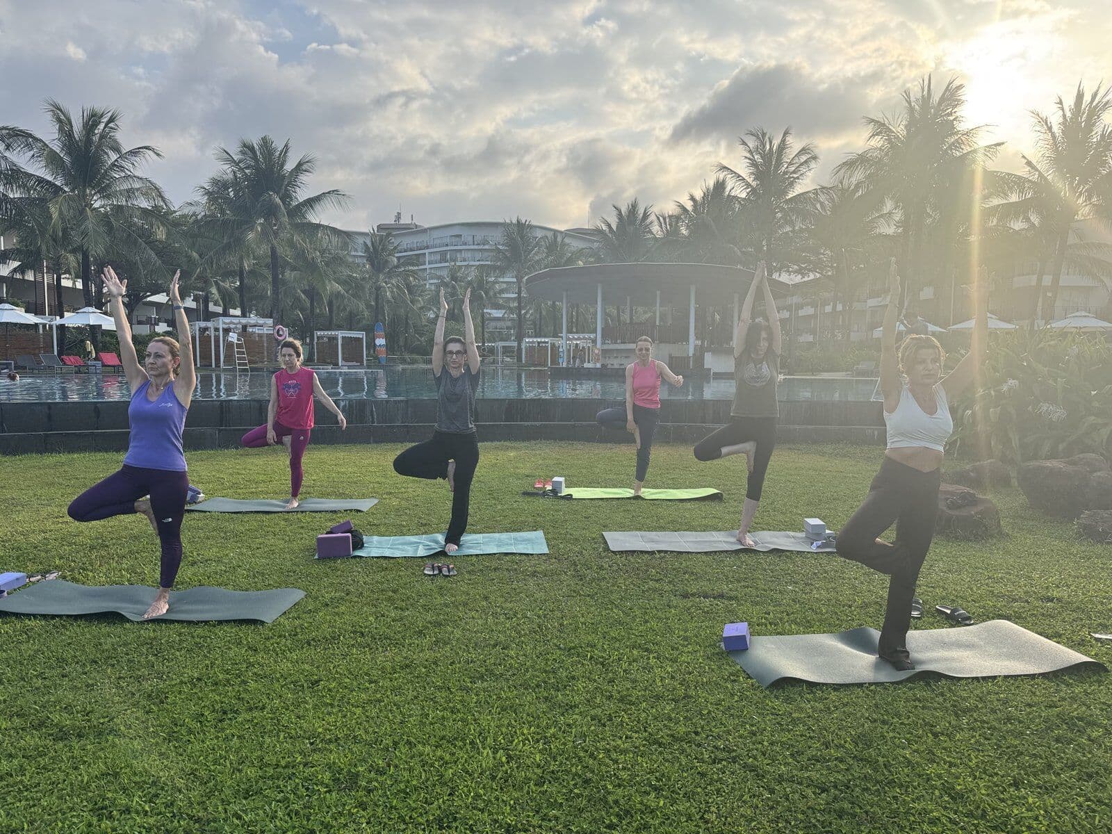 Outdoor yoga practice at sunset with palm trees